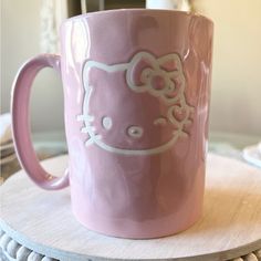 a pink hello kitty mug sitting on top of a table