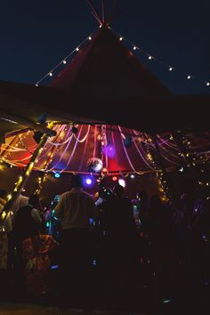 people standing under a tent with lights on it