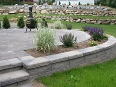 a stone patio surrounded by grass and flowers