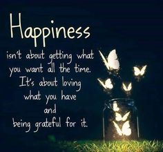 a jar filled with butterflies sitting on top of a grass covered field next to a sign that says happiness