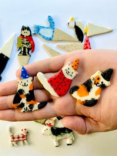 a hand holding several small ceramic cats and dogs