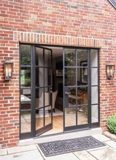 an open door to a brick building with glass doors and black trim on the outside