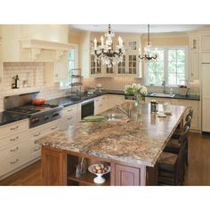 a large kitchen with an island and chandelier hanging from the ceiling above it