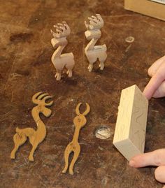 three wooden animals sitting on top of a counter next to a block of wood and a ruler