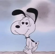 a cartoon dog with black and white ears on it's head standing in the sand