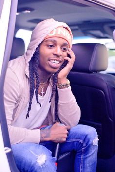 a young man sitting in the back seat of a car talking on a cell phone