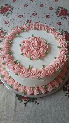 there is a cake with pink frosting roses on it and green leaves around the edges