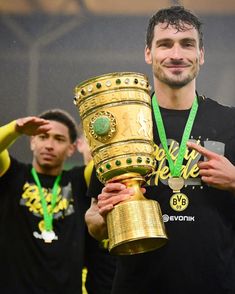 a man holding a trophy in front of two other men