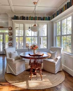 a living room filled with white furniture and lots of books on the shelves above it