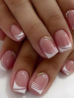 a woman's hands with pink and white nail polishes on their nails, holding a manicure