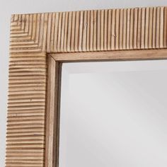 a wooden frame mirror hanging on the wall with a white wall in the back ground