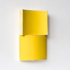 a piece of yellow painted paper on a white wall