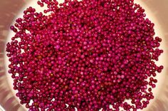 a white bowl filled with red beads on top of a table