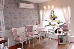 a room filled with lots of white furniture and pink flowers on the wall behind it