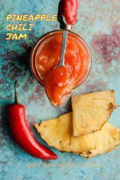 pineapple chilli jam in a glass jar with a spoon next to it and a red pepper on the side