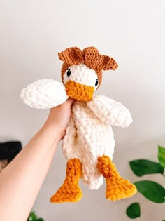 a crocheted duck is held up in the air by someone's hand