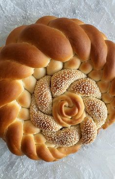 a braided bread with sesame seeds in the center on a white tablecloth background