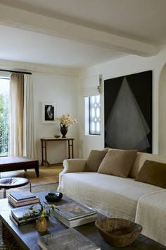 a living room filled with furniture and a painting on the wall above it's coffee table