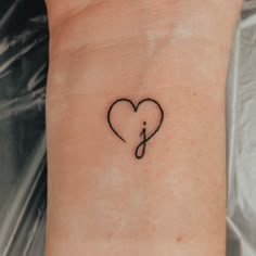 a small tattoo on the wrist of a woman with a musical note in the shape of a heart