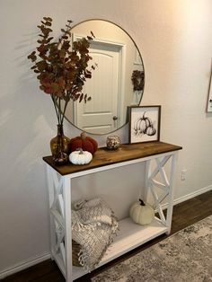 a white shelf with a mirror and some pumpkins on it in front of a door