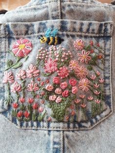 the back of someone's jean jacket with flowers and a bee embroidered on it