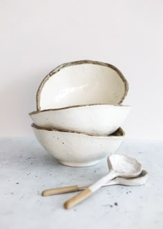 three bowls with spoons sitting on a table