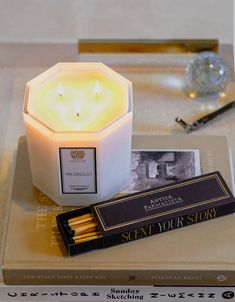 a white candle sitting on top of a table next to a book and some matches