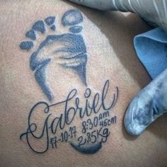 a tattoo on the back of a man's stomach with an image of a baby foot