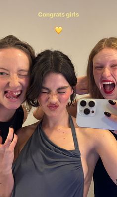 three women taking a selfie in front of a mirror