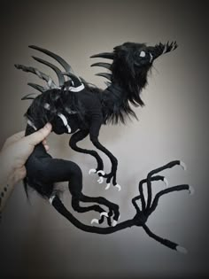 a hand holding a black dragon made out of fabric