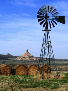 a windmill and hay bales in an open field