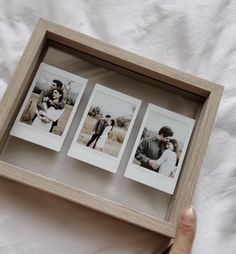 three polaroid photos in a wooden box on a white sheet with a hand holding one