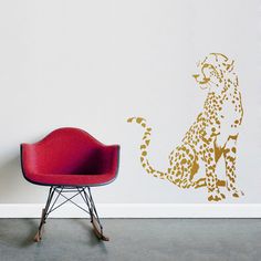 a red chair sitting in front of a wall with a leopard decal on it