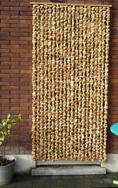 a woven wall hanging next to a potted plant on the side of a building