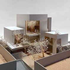 an architectural model of a house with trees and bushes in the front, surrounded by concrete blocks