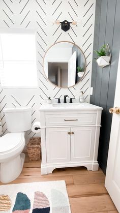 a bathroom with a white toilet sitting next to a sink and a mirror on the wall