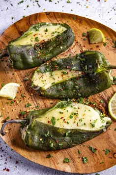 three stuffed jalapenos on a wooden platter with lemon wedges and garnishes