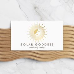 a white and gold business card with the words solar goddess on it in front of a marble background