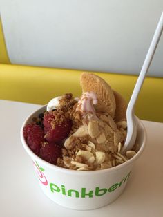 a bowl filled with granola, raspberries and ice cream on top of a table