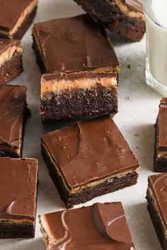 chocolate brownies with peanut butter frosting on a table next to a glass of milk