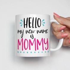 a woman's hand holding a coffee mug with the words hello my new name is mommy