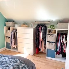 a bedroom with an open closet and clothes hanging on the wall, next to a bed