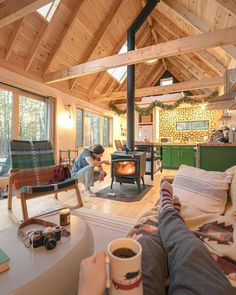 a person sitting on a couch with a cup of coffee in front of an open fire place