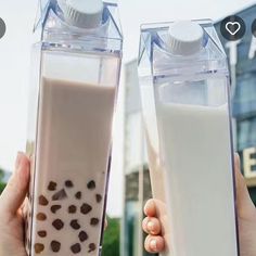 two people holding up milk in front of a building