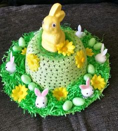 a cake decorated with green grass and yellow flowers is sitting on a table next to some bunnies