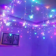 a room filled with lots of lights and butterflies hanging from it's ceiling above a bed