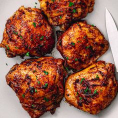 four pieces of cooked chicken on a plate with a knife and fork next to it