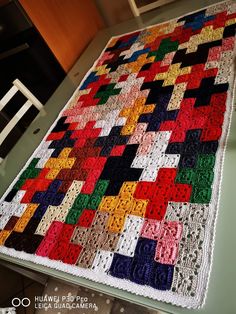 a multicolored quilt sitting on top of a table next to a white chair