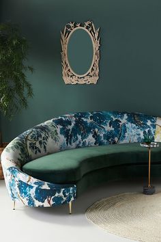 a green couch sitting in front of a mirror on a wall next to a rug