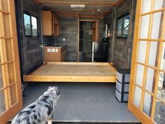 a dog is looking out the back door of a tiny house that's being built